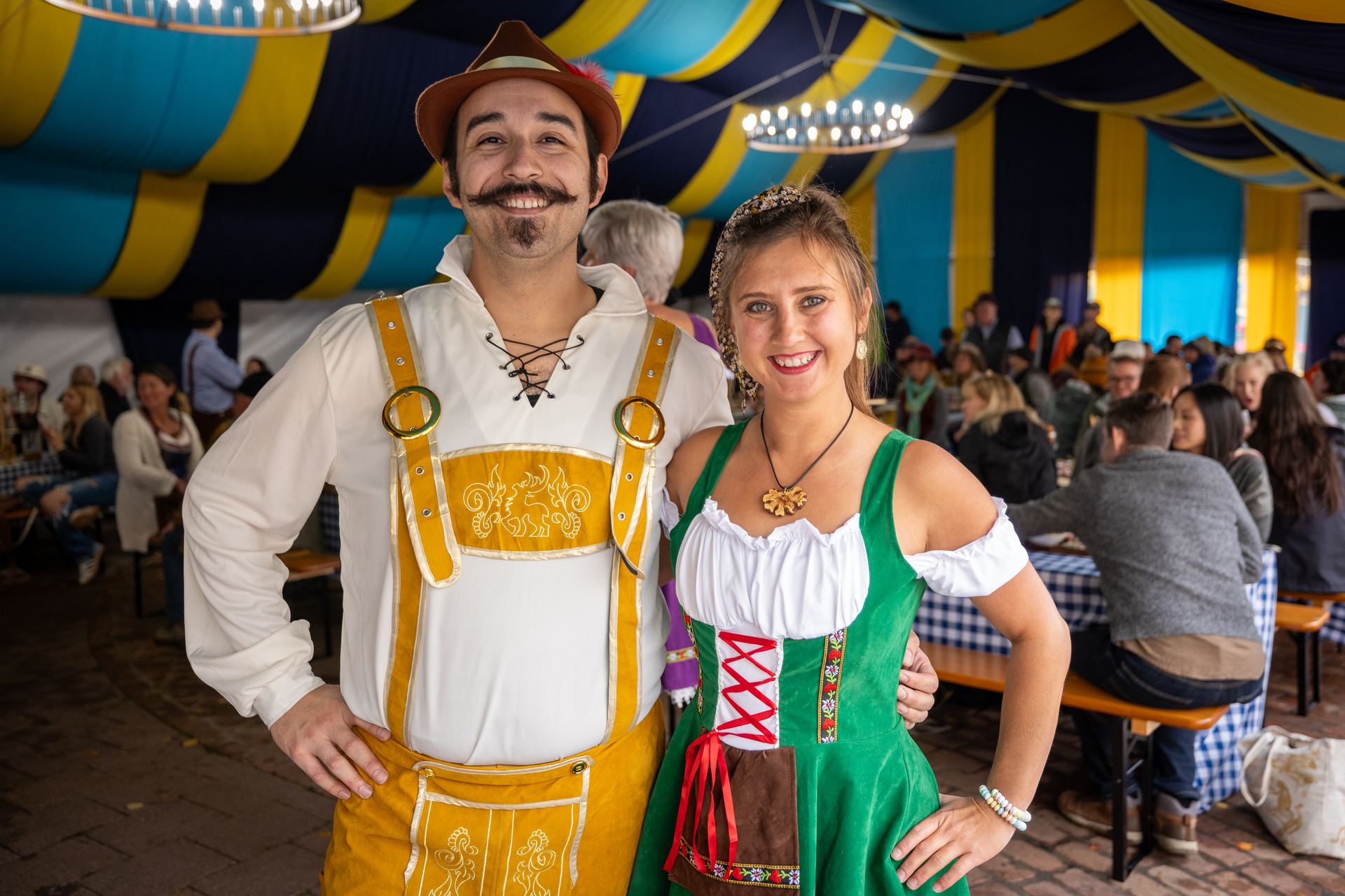 A couple in traditional Bavarian dress smiling together inside the festival tent
