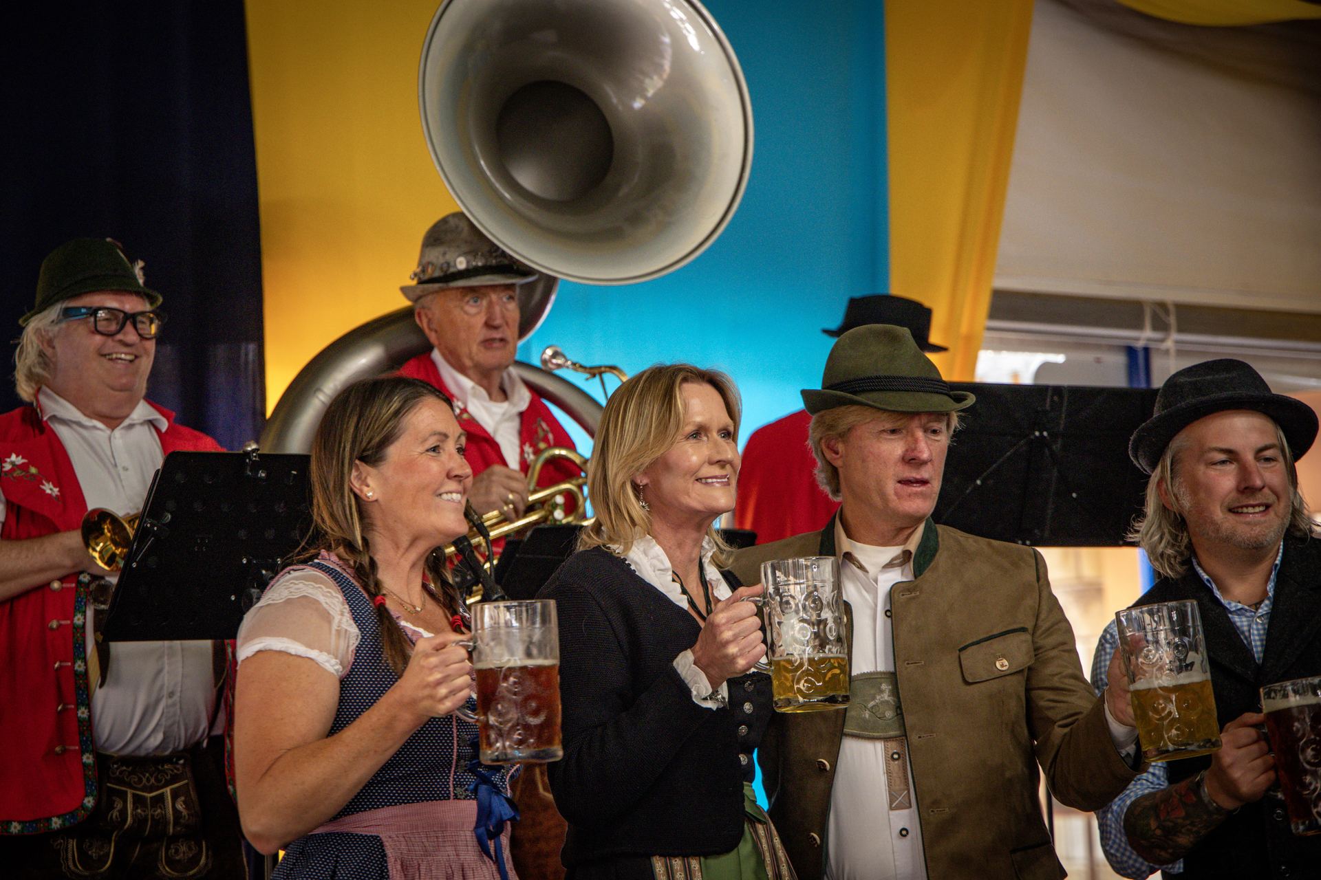 Guests raising their steins in the tent with the oompah band playing behind them